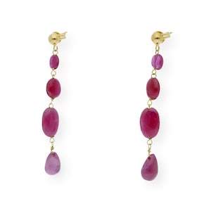 Puede incluir: Un par de pendientes largos y colgantes con una cadena dorada y múltiples piedras preciosas ovaladas y en forma de lágrima de color rosa.