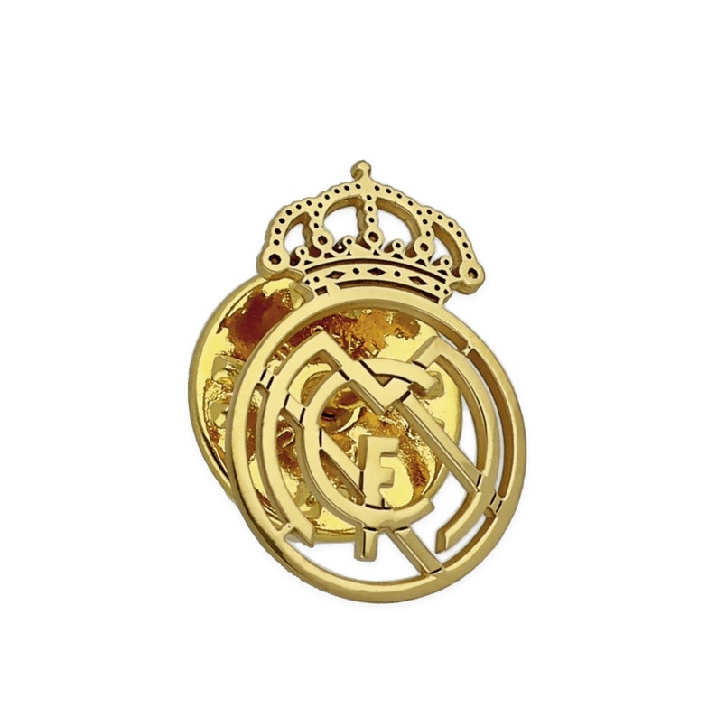 May include: A gold-colored metal pin featuring the Real Madrid crest with a crown on top.