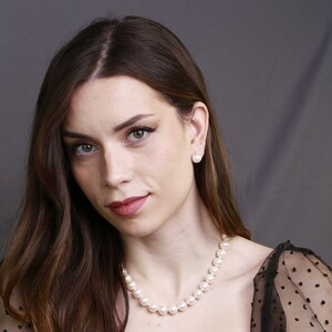 Puede incluir: Una mujer con el pelo largo y casta&ntilde;o que lleva una blusa negra transparente con pendientes de perlas blancas y un collar de perlas.