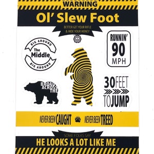 Peut inclure: Un panneau d'avertissement à rayures noires et jaunes, représentant un ours de dessin animé avec un motif en spirale. Le texte indique "WARNING Ol' Slew Foot" et comprend des détails tels que "BETTER GET YOUR RIFLE & HIDE YOUR HONEY", "RUNNIN' 90 MPH", "30 FEET TO JUMP", "NEVER BEEN CAUGHT", "NEVER BEEN TREED", et "HE LOOKS A LOT LIKE ME".