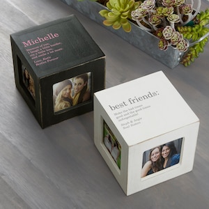 May include: Two white wooden photo cube boxes with black and white photos of two women. The top of each box has a personalized message. The first box says "Michelle Because of you, I laugh a little harder, cry a little less, and smile a lot more. Love, Katie Besties Forever". The second box says "best friends: Make the bad times good and the good times unforgettable! Steph & Angie Soul Sisters".