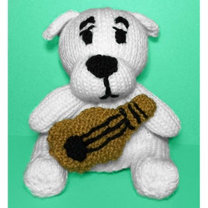 Puede incluir: Juguete de peluche blanco de punto en forma de perro que sostiene una guitarra marrón con detalles negros. El perro tiene ojos negros y una nariz negra.