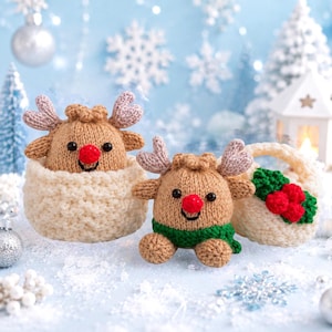 May include: Two tan knitted reindeer figures with red noses and light brown antlers. One reindeer sits inside a textured cream-colored bowl, while the other sits beside a cream-colored basket decorated with green leaves and red berries.