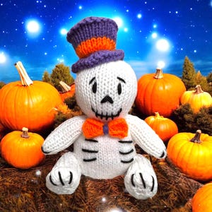 Peut inclure: Poupée squelette d'Halloween tricotée à la main, portant un chapeau haut de forme violet et orange et un nœud papillon orange. La poupée blanche est entourée de citrouilles orange de différentes tailles, sur fond de ciel étoilé.