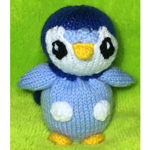 May include: A blue and white knitted penguin toy with black eyes and a yellow beak.