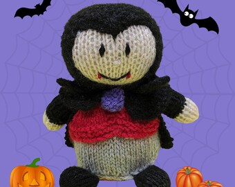 May include: A knitted plush toy vampire with a red and gray costume, black cape, and fangs. The toy is sitting on a purple background with a spiderweb pattern and two black bats.
