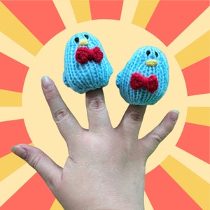 May include: Two blue knitted finger puppets with red bow ties. The puppets are worn on a person's fingers.