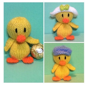 May include: Three knitted yellow duck plushies. One duck is wearing a white hat with a green bow. Another duck is wearing a blue hat. The third duck is holding a chocolate egg.