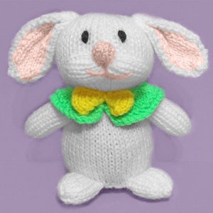May include: A white knitted bunny rabbit toy with pink ears and a green and yellow bow tie.
