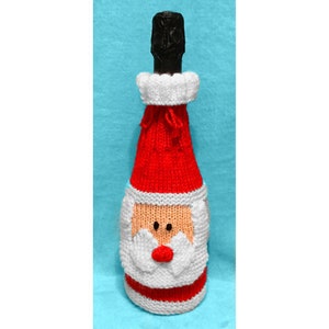 May include: A knitted Santa Claus bottle cover in red, white, and peach colors. The cover has a white pom-pom on top and a white beard with a red nose.