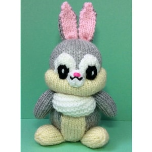 May include: A grey knitted bunny rabbit with pink ears, white and cream coloured accents, and black eyes.