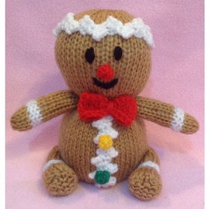 May include: A knitted gingerbread man toy with white icing, red bow tie, and colorful candy decorations.