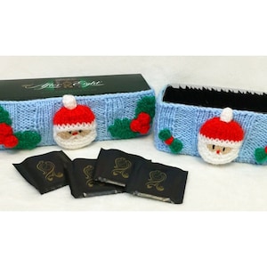 May include: A blue knitted box cover with a Santa Claus and holly design. The box is filled with After Eight chocolate mints.