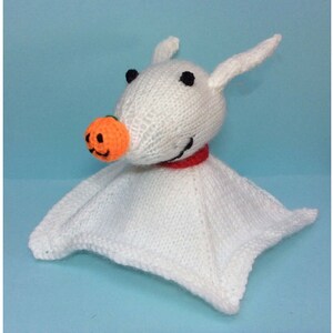 May include: A handmade white knitted Zero plush toy from The Nightmare Before Christmas. The plush features black eyes, a pumpkin nose, and a red collar. The toy has a soft, blanket-like body.