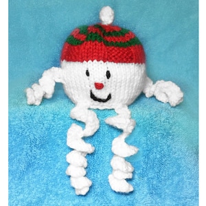 May include: White knitted snowman ornament with a red and green striped hat and a white pom pom on top. The snowman has a black smiling mouth, two black eyes, and a red nose.