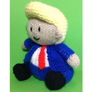 May include: A knitted toy doll with yellow hair, a blue jacket, a red tie, and black shoes.