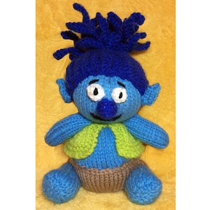 May include: A blue knitted troll doll with green vest and brown diaper. The troll has a blue mohawk and a big smile.
