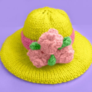Peut inclure: Un chapeau de soleil en tricot jaune avec une fleur rose et verte.