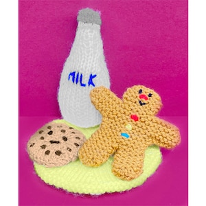 May include: A knitted gingerbread man, a knitted milk bottle with the word "MILK" embroidered on it, and a knitted chocolate chip cookie on a knitted green and yellow surface.