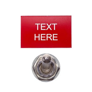 May include: A red rectangular plate with the text "TEXT HERE" in silver lettering above a chrome toggle switch. The switch has a silver lever and a hexagonal base.