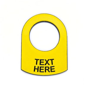 May include: Yellow plastic ring with a hole in the center and the text "TEXT HERE" printed in black.