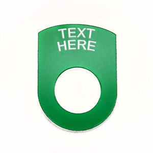 May include: Green plastic button with a white ring and the text "TEXT HERE" in white.