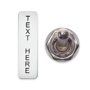 Puede incluir: Un interruptor de palanca plateado con una etiqueta rectangular blanca que dice "TEXT HERE".