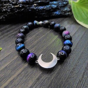 May include: A black beaded bracelet with a crescent moon charm. The beads have a galaxy-like iridescent shimmer.