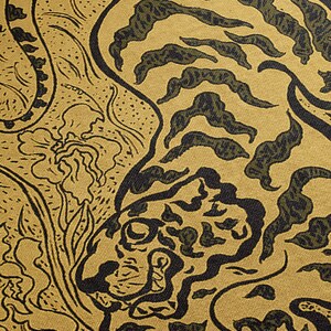 Pu&ograve; includere: Primo piano di un tessuto con un motivo a tigre in nero e verde su sfondo dorato. Il viso della tigre &egrave; visibile nell'angolo in basso a destra dell'immagine.