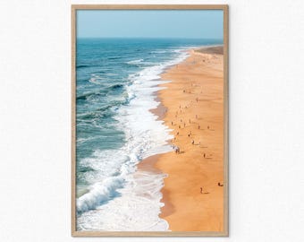 May include: An aerial view of a sandy beach with blue ocean waves crashing on the shore. The beach is crowded with people enjoying the sun and surf.
