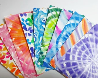 May include: Ten watercolor painted cards with different designs. The cards are arranged in a fan shape, with the purple card on top. The designs include flowers, swirls, and abstract patterns.