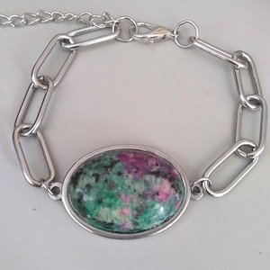 May include: A silver chain bracelet with a large oval-shaped green and pink gemstone.