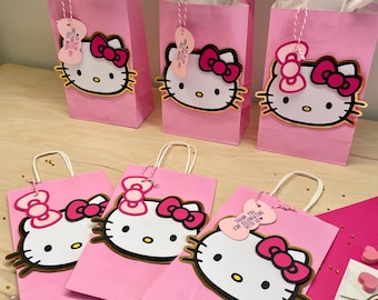 May include: Pink Hello Kitty favor bags with gold trim and pink bows. The bags have a thank you tag with the text "Thank you for celebrating with us".