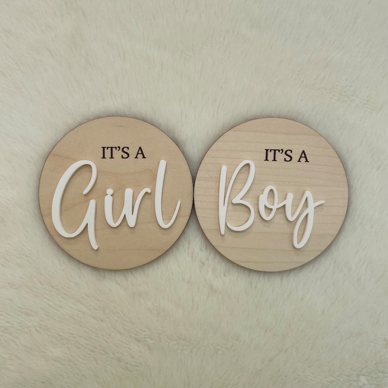 May include: Two round wooden signs with the text "It's a Girl" and "It's a Boy" in white lettering.