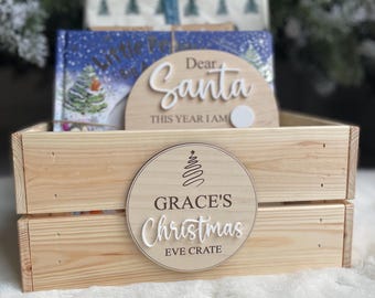Pode incluir: Caixa de madeira para a véspera de Natal com uma placa redonda que diz "Grace's Christmas Eve Crate" com um design de árvore de Natal estilizado. A placa também tem uma placa redonda menor que diz "Caro Papai Noel Este ano eu sou..."