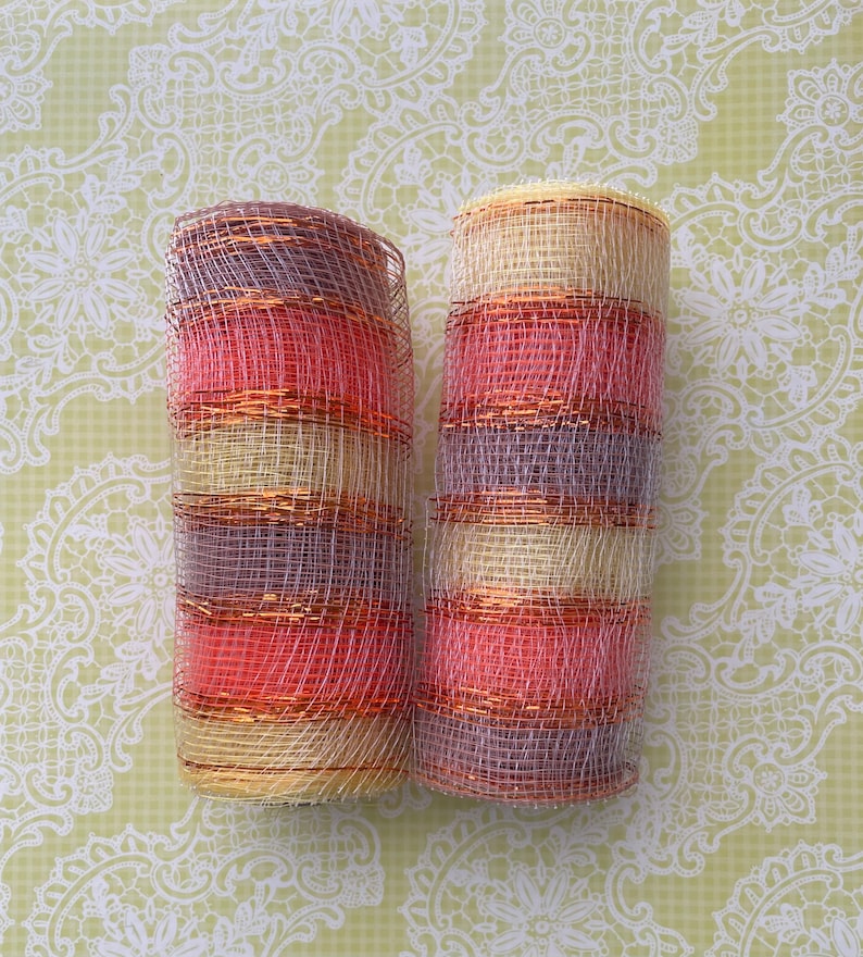Pu&ograve; includere: Due rotoli di nastro decorativo a rete con un motivo a strisce in tonalit&agrave; di rosa, beige e viola. Il nastro &egrave; realizzato in un materiale a rete fine con un effetto metallizzato.