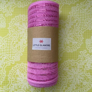 Pu&ograve; includere: Un rotolo di nastro in rete rosa con un'etichetta marrone su cui &egrave; scritto "Little Glamore for Every Occasion".