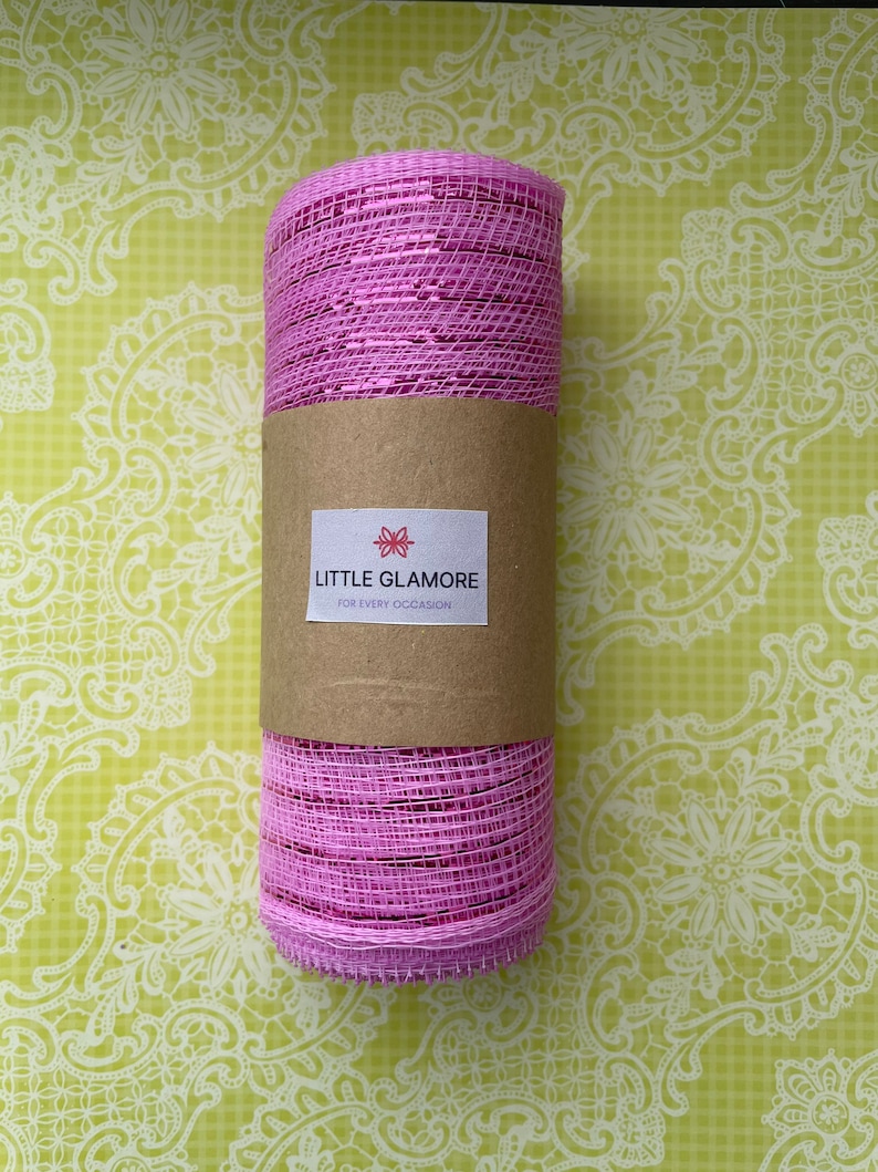 Pu&ograve; includere: Un rotolo di nastro in rete rosa con un'etichetta marrone su cui &egrave; scritto "Little Glamore for Every Occasion".