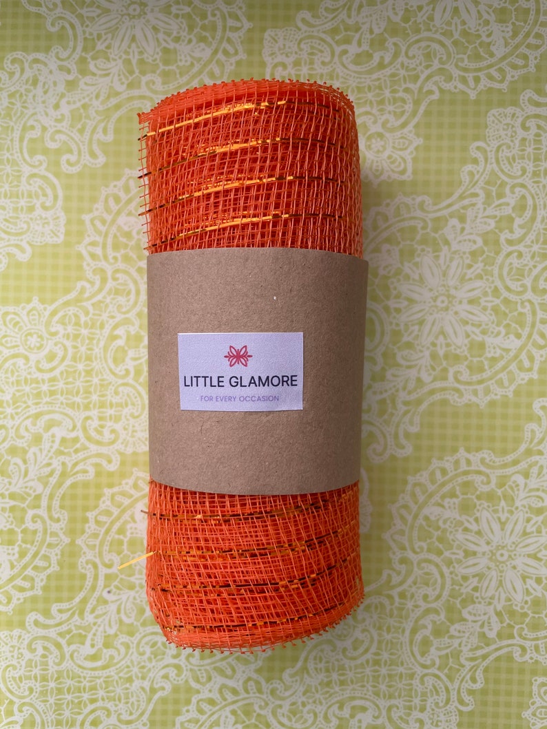 Pu&ograve; includere: Rotolo di nastro in rete arancione e oro con un'etichetta marrone che dice "Little Glamore for Every Occasion".
