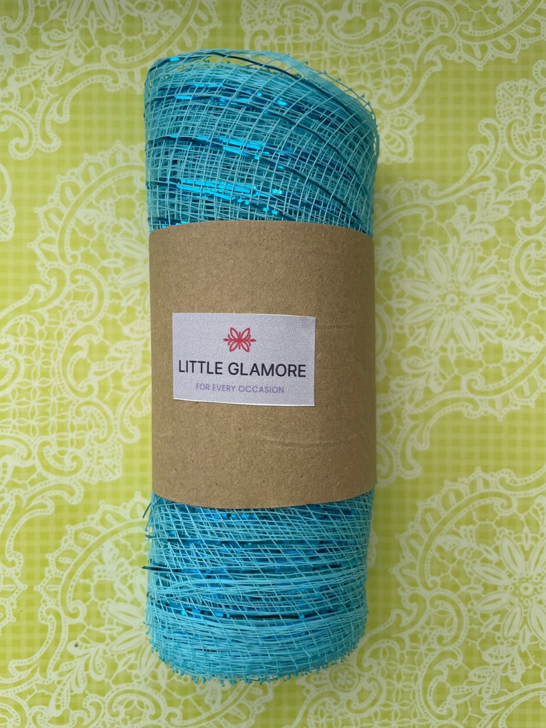 Pu&ograve; includere: Un rotolo di nastro in rete metallica blu con un'etichetta marrone su cui &egrave; scritto "LITTLE GLAMORE FOR EVERY OCCASION".