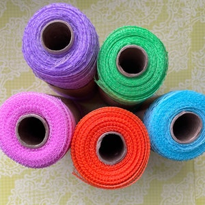 Pu&ograve; includere: Cinque bobine di nastro a rete di diversi colori. Le bobine sono viola, verde, rosa, arancio e blu.