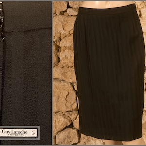 Peut inclure: Une jupe noire à rayures verticales. La jupe a une fermeture éclair et une étiquette qui indique "Guy Laroche Boutique - Paris" et "44".