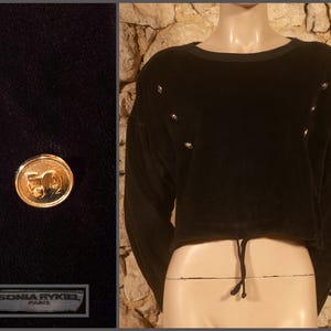 Può includere: Top corto in velluto nero con maniche lunghe e vita con coulisse. Il top presenta bottoni dorati decorativi e scollatura rotonda. Un primo piano mostra un bottone dorato con il numero "50" e l'etichetta del marchio "SONIA RYKIEL PARIS".