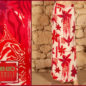 May include: A white maxi skirt with a red and white floral print. The skirt has a high waist and a flowy silhouette. The fabric is lightweight and has a silky feel. The skirt features the text "KENZO JUNGLE" printed on the bottom left corner.