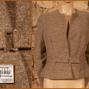 May include: A brown tweed blazer with a silver buckle closure. The jacket has a notched collar and long sleeves. The label reads "Angelo Tarlazzi Paris". The blazer is displayed on a mannequin.