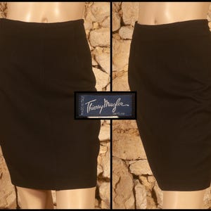 May include: A black pencil skirt with a fitted silhouette. The skirt features a high waist and a knee-length hemline. A label with the text "Thierry Mugler active" is visible.