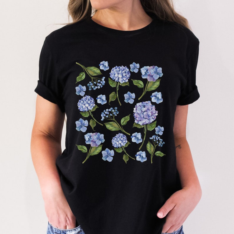 May include: Black t-shirt with a floral print featuring blue hydrangeas and green leaves.