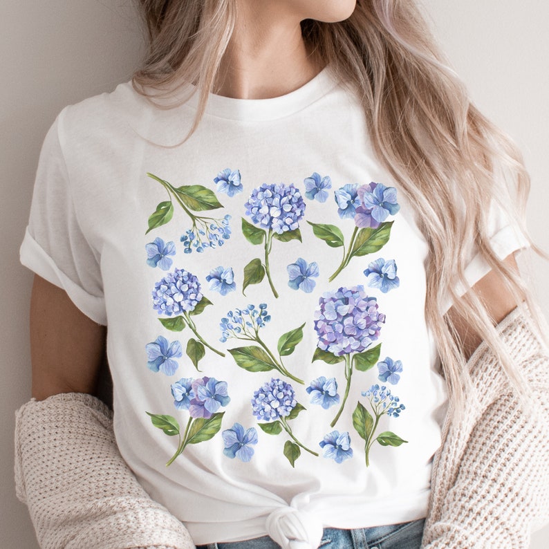 May include: White t-shirt with a floral print featuring blue hydrangeas and green leaves.