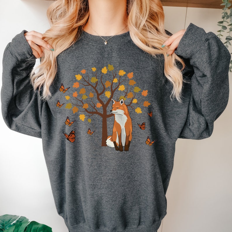 May include: A gray sweatshirt with a graphic of a fox sitting in front of a tree with orange leaves and butterflies.