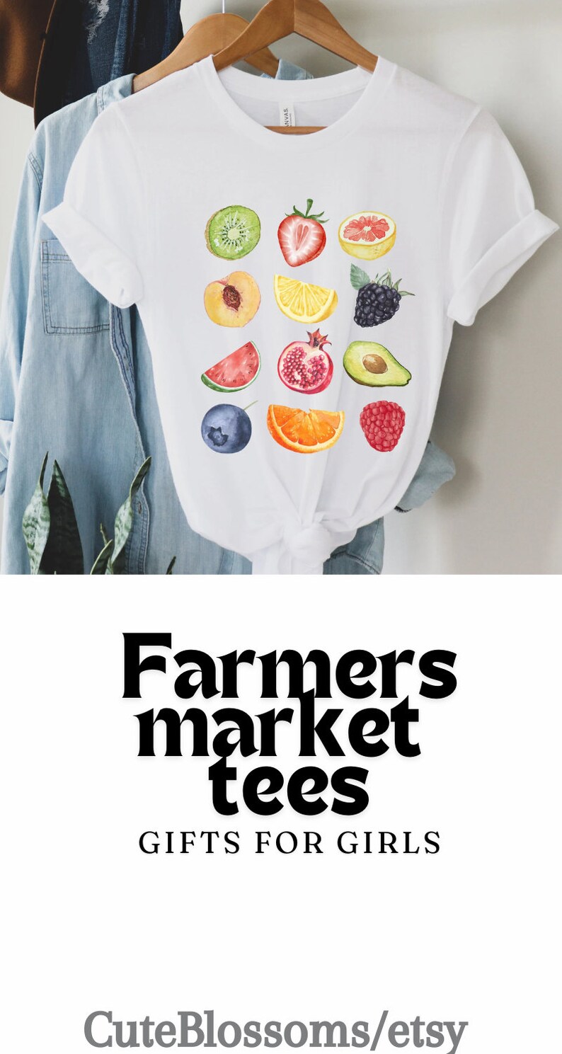 May include: White t-shirt with a colorful watercolor design of various fruits and berries. The text "Farmers market tees" and "Gifts for girls" is printed below the design. The text "CuteBlossoms/etsy" is printed below the text.